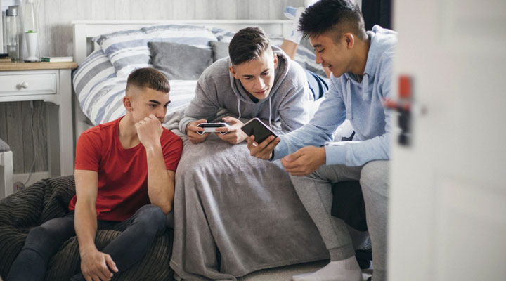 اهمیت آموزش مسائل جنسی به کودکان + راهنمای آموزش در سنین مختلف 6 آموزش مسائل جنسی به نوجوانان ـ چند نوجوان در حال صحبت و کندوکاو در اینترنت