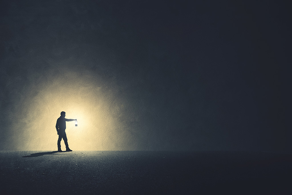 مرد کنار دیوار با چراغ در دست در تاریکی